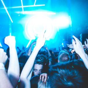 A lively nightclub scene with people dancing under bright blue lights.