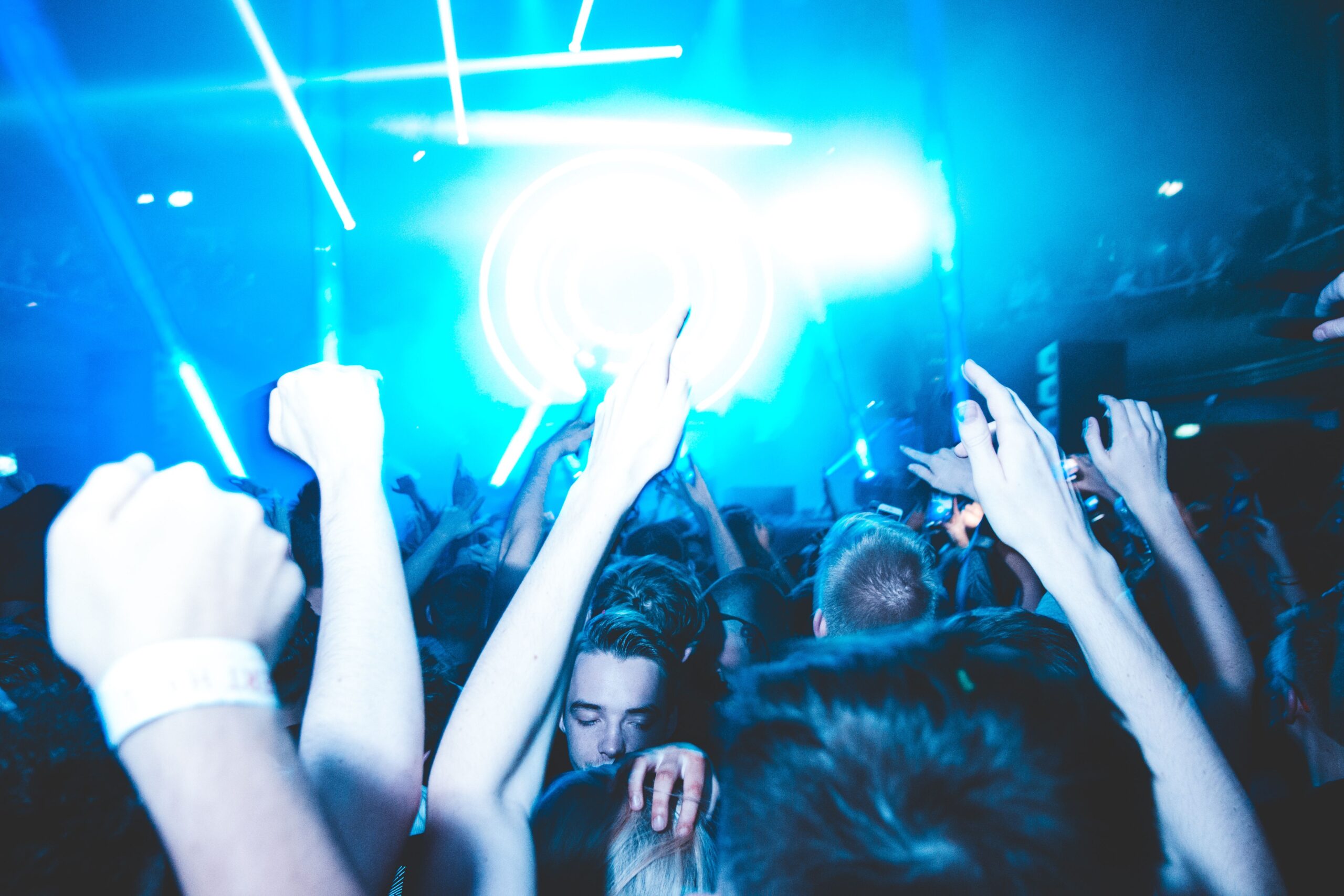 A lively nightclub scene with people dancing under bright blue lights.